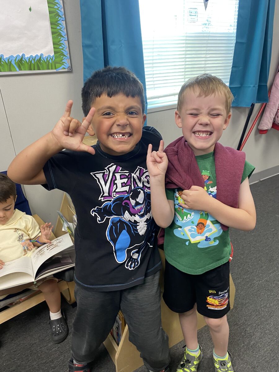 Two preschool boys making silly faces and smiling together in the classroom