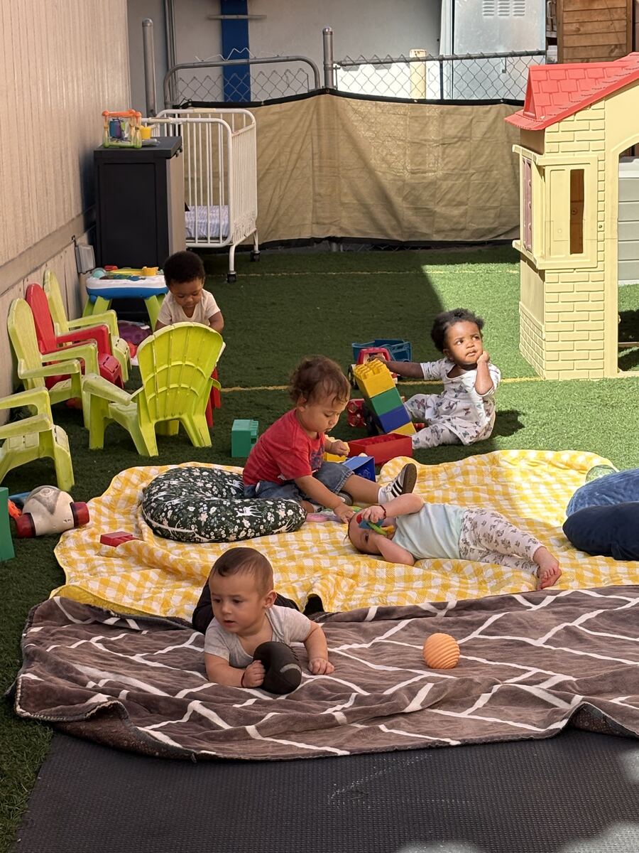 Babies and toddlers playing on blankets and soft mats in the outdoor play area